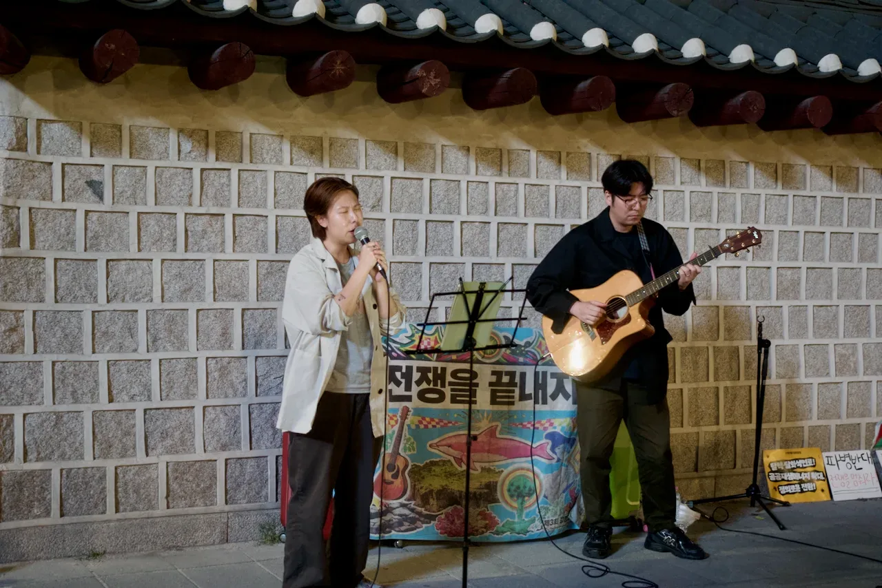 '전쟁을 끝내자!' 현수막 앞에서 노래하는 음악가들